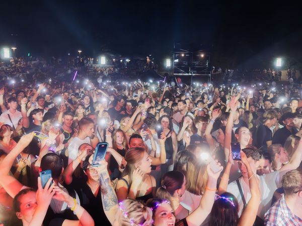 Feiernde Menschen halten ihre Handys mit Taschenlampenfunktion in die Luft und feiern