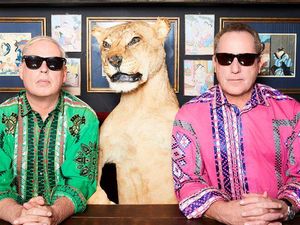 Die beiden Musiker von OMD schauen mit aufgesetzten Sonnenbrillen in die Kamera. Zwischen ihnen sitzt eine Löwin.