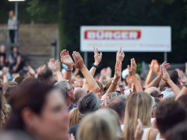 Feiernde Menschen heben die Hände zum Himmel auf der BÜRGER Freilichtbühne