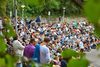 Blick auf eine seitliche Tribüne der BÜRGER Freilichtbühne. Menschen sitzen auf den Steinen und hören dem Konzert zu.