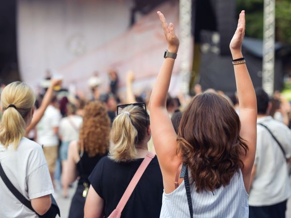 Eine Frau hebt die Hände und klatscht zur Musik von Clueso
